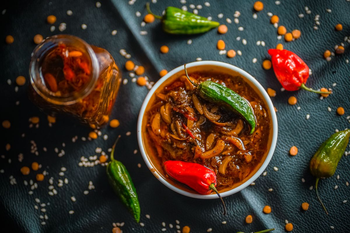 Bowl of spicy naga chilli dish with fresh red and green chillies on a dark surface
