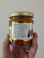 Hand holding a jar of spice with a label showing ingredients.