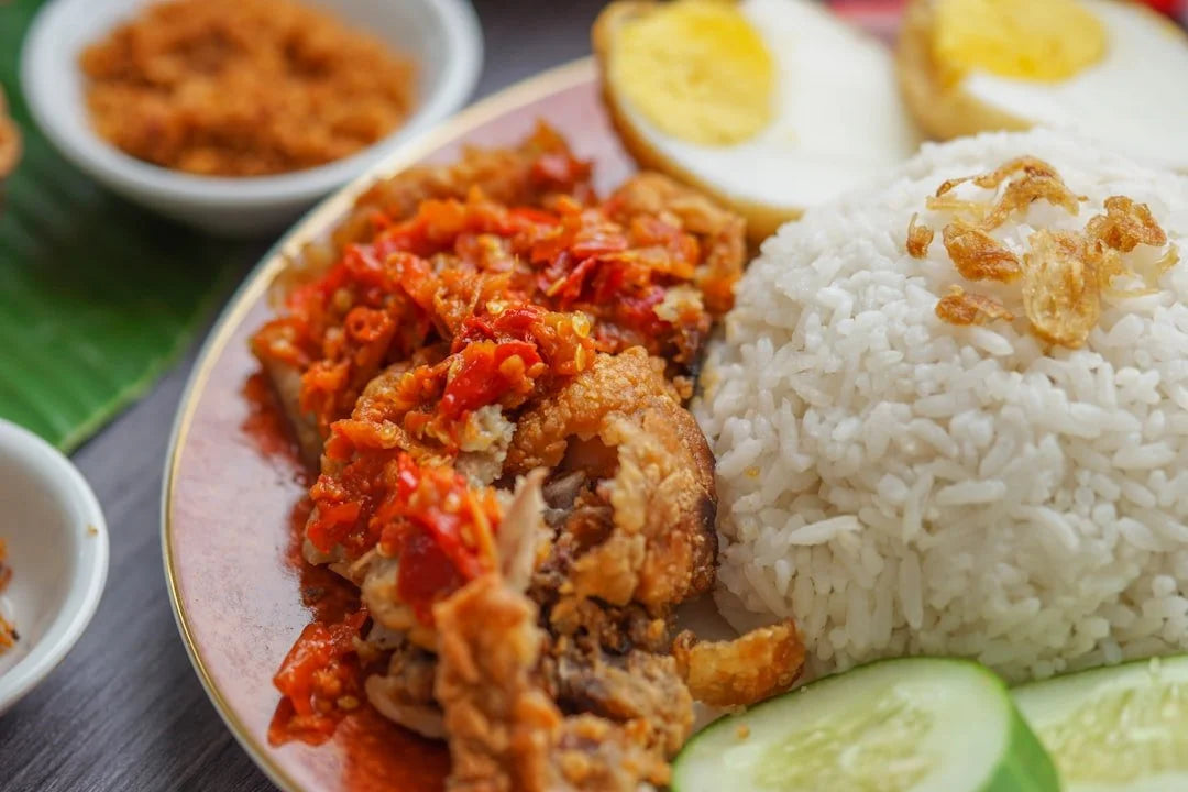 Plated dish with rice, fried chicken, and vegetables on a wooden table.